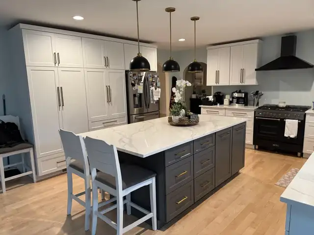 Custom kitchen with white full-height cabinets, a charcoal island with a white quartz top and black pendant lights