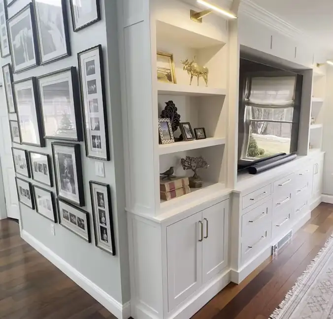 Custom painted built-in cabinet with open shelves and closed storage beside a hallway gallery wall