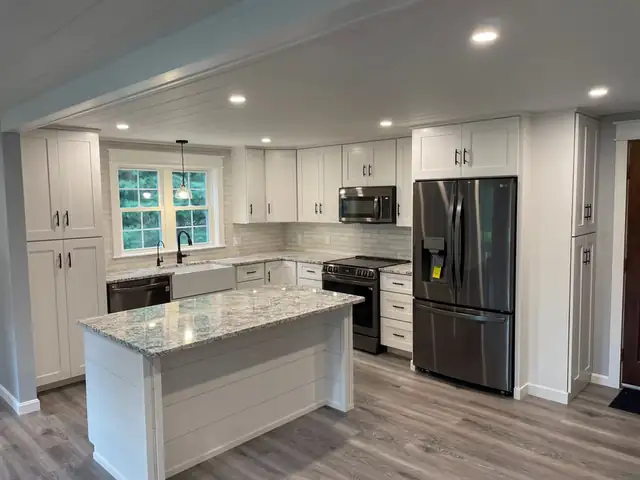 White Shaker kitchen with a shiplap-sided island and granite countertop