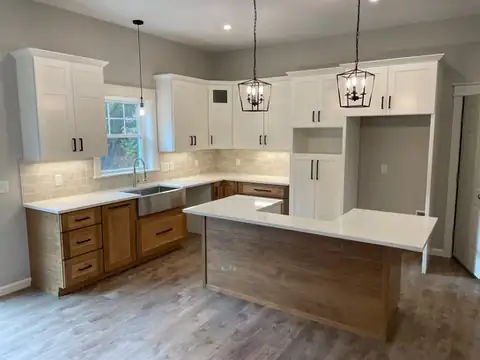 Kitchen with white upper cabinets, wood-tone lower cabinets, a farmhouse sink and a reclaimed wood island